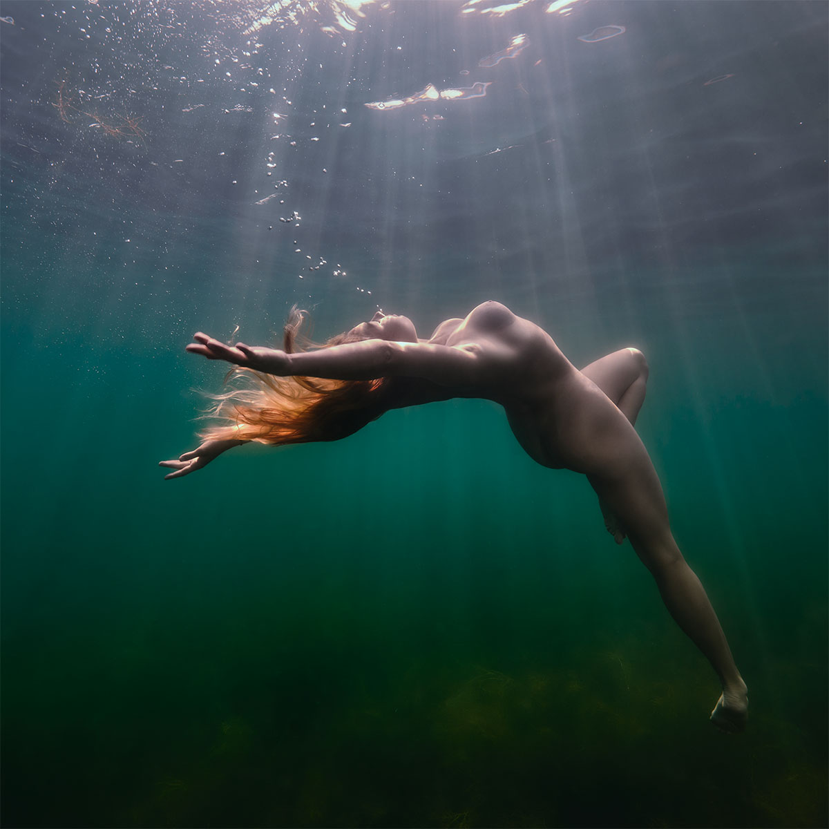 Sinnliche Unterwasser-Aktfotografie: schwebende Frau im goldenen Sonnenlicht in einem klaren See bei Weimar