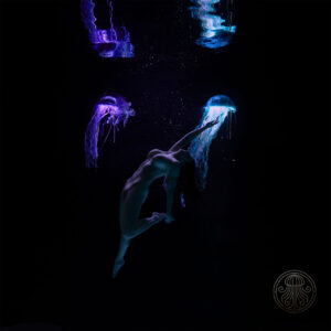 Unterwasser FineArt Aktfoto einer schwebenden Frau zwischen zwei leuchtenden LumiJelly™ Lichtskulpturen, fotografiert von Stern Photography.